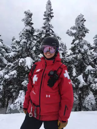 Sabina Schulz in her red ski patrol jacket, in front of snowy trees